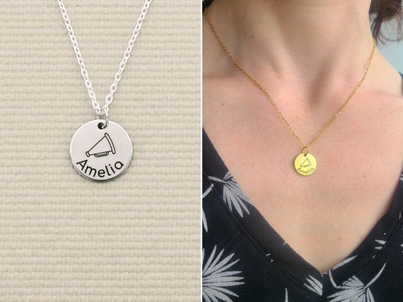 May include: Silver necklace with a round pendant featuring a megaphone and the name Amelia engraved on it.