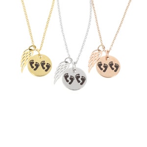 Puede incluir: Tres collares de oro, plata y oro rosa con un pequeño dije de ala de ángel y un dije redondo con un diseño de huella.
