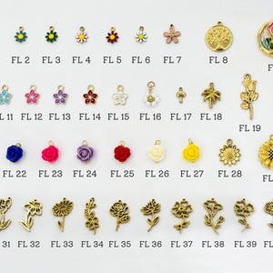 K&ouml;nnte beinhalten: Eine Sammlung von 41 Charms mit Blumenmotiven in Gold und verschiedenen Farben. Die Charms zeigen detaillierte florale Designs, wie Sonnenblumen, Rosen und G&auml;nsebl&uuml;mchen, wobei einige farbige Emaille-Akzente aufweisen. Jeder Charm ist mit einer Nummer versehen.