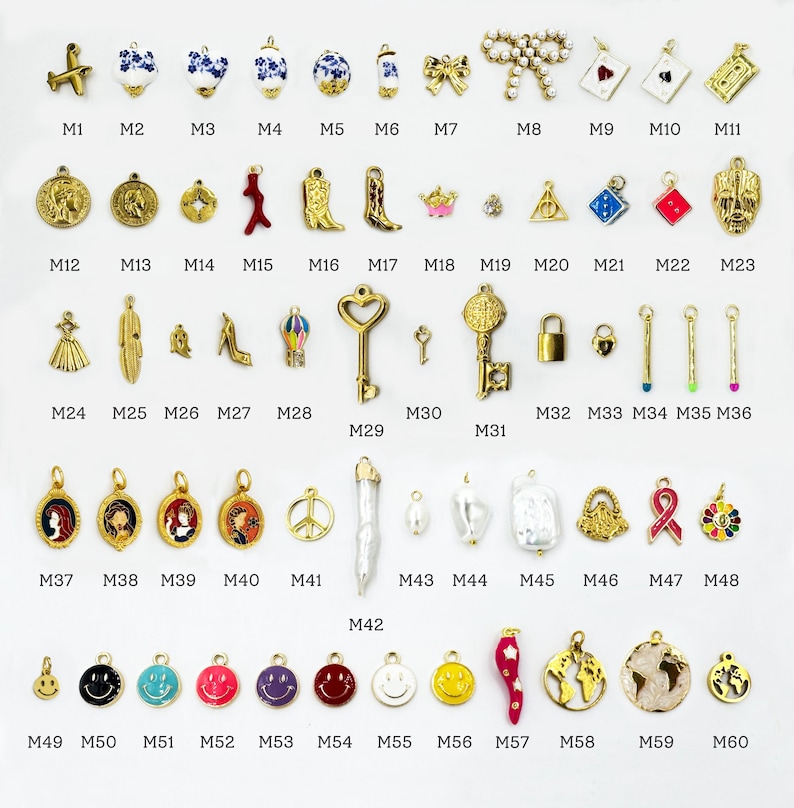 K&ouml;nnte beinhalten: Eine Sammlung goldfarbener Charms mit verschiedenen Designs, darunter ein Flugzeug, Blumen, eine Schleife, ein Schl&uuml;ssel, ein Schloss und ein Smiley. Einige Charms haben farbige Emaille-Details. Die Charms sind in Reihen und Spalten angeordnet.
