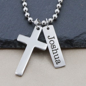 Peut inclure: Un collier en chaîne argent avec un pendentif en forme de croix argent et un pendentif en forme de plaque argent gravé du nom "Joshua".