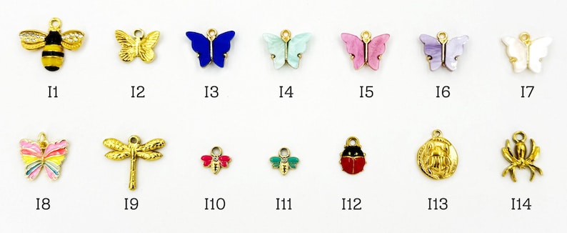 K&ouml;nnte beinhalten: Eine Sammlung kleiner, farbenfroher Insekten- und Schmetterlingsanh&auml;nger. Die Anh&auml;nger umfassen eine goldene Biene mit schwarzen Streifen, einen goldenen Schmetterling, einen blauen Schmetterling, einen mintgr&uuml;nen Schmetterling, einen rosa Schmetterling, einen lavendelfarbenen Schmetterling, einen wei&szlig;en Schmetterling, einen rosa Schmetterling, eine goldene Libelle, eine rote Biene, eine gr&uuml;ne Biene, einen roten Marienk&auml;fer, ein goldenes Medaillon und eine goldene Spinne.
