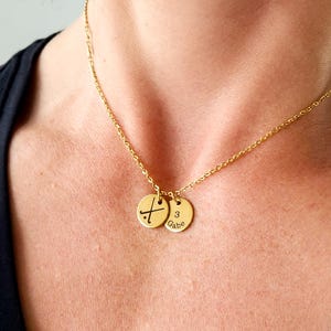 model's neck with black shirt on, wearing gold necklace with two discs showing field hockey symbol and number and name of player