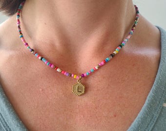 May include: A colorful beaded necklace with a gold pendant featuring the letter "L".