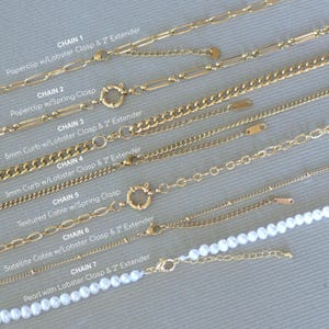 K&ouml;nnte beinhalten: Sieben goldfarbene Halsketten mit verschiedenen Kettenstilen, darunter Paperclip-, Curb- und Kabeldesigns. Jede Halskette hat einen Verschluss und eine 5 cm Verl&auml;ngerung. Eine Halskette enth&auml;lt wei&szlig;e Perlen.