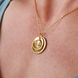 May include: Gold necklace with a layered pendant featuring the names Charlotte, Noah, Sophia, and Mia, with a clear crystal in the center.