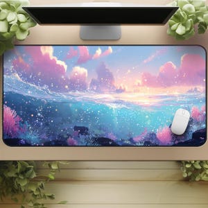 May include: A rectangular desk mat with an ocean and sunset design. The mat features shades of blue, pink, and purple, with a white computer mouse on the right. The mat is designed to protect the desk surface, and is approximately 80 cm in length.