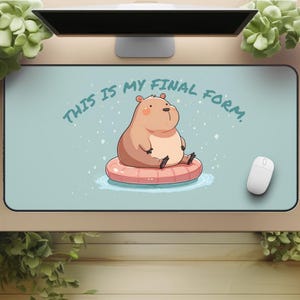 Op de afbeelding: Een rechthoekige muismat met een cartoonillustratie van een bruine nijlpaard die op een roze opblaasbare ring in het water zit. De tekst "THIS IS MY FINAL FORM." is gedrukt in turquoise. Een witte muis staat rechts.