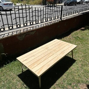 May include: A rectangular wooden coffee table with a light wood finish. The table has four legs and a slatted top. The table is approximately 48 inches long and 24 inches wide.
