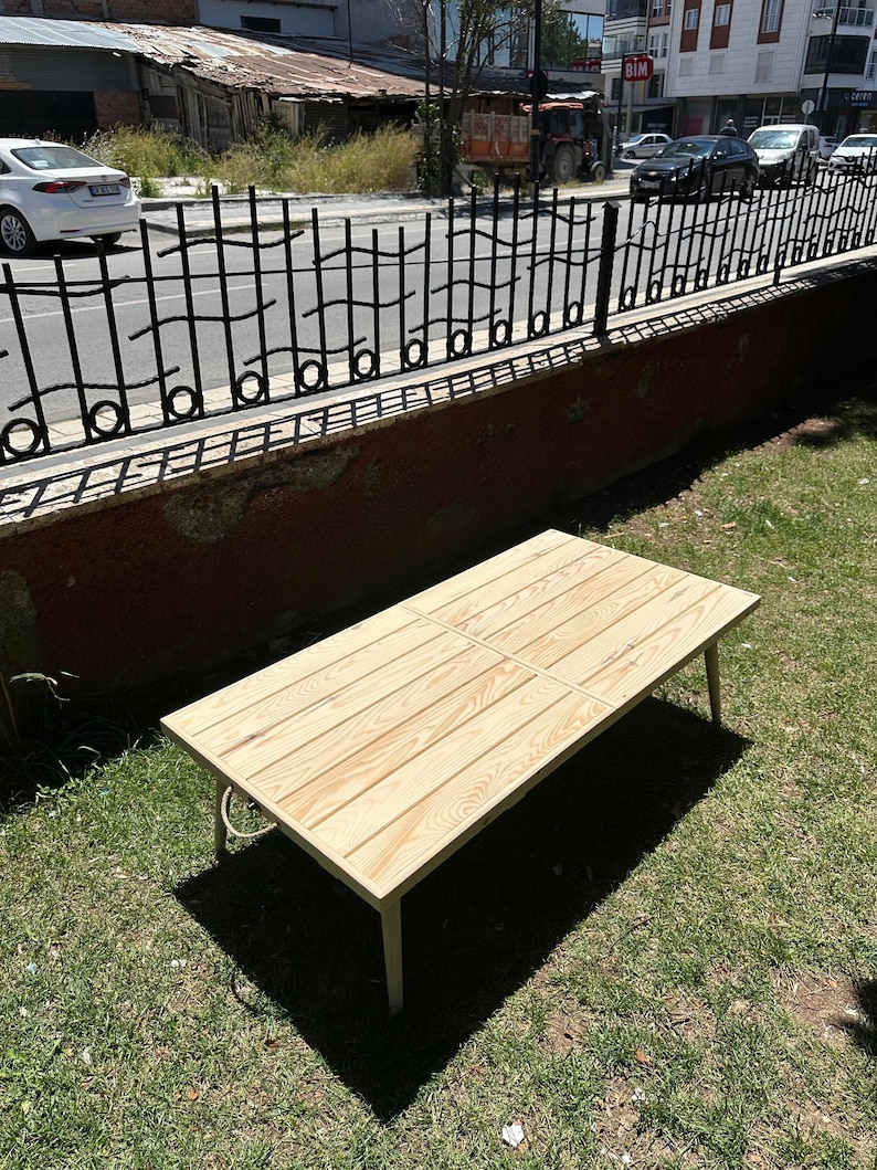 May include: A rectangular wooden coffee table with a light wood finish. The table has four legs and a slatted top. The table is approximately 48 inches long and 24 inches wide.