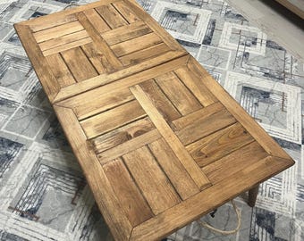 May include: A rustic wooden coffee table with a unique slatted design. The table has a natural wood finish and is supported by four legs. The table is sitting on a patterned rug.