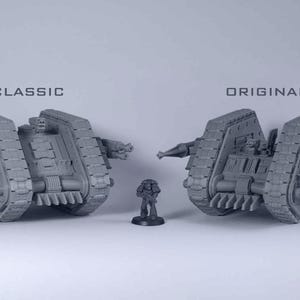 May include: Two grey unpainted miniature tanks and one small soldier figurine. The tank on the left is labelled CLASSIC and the tank on the right is labelled ORIGINAL. Both tanks feature heavy treads, side-mounted cannons, and front-facing blades.