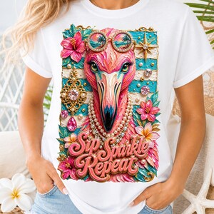 May include: White t-shirt featuring a vibrant flamingo design. The flamingo wears sunglasses and a pearl necklace, surrounded by flowers and jewels. The text "Sip Sparkle Repeat" is displayed in pink script.