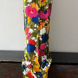 May include: A sleeveless maxi dress with a vibrant floral print featuring pink, yellow, red, blue, and green flowers on a white background.