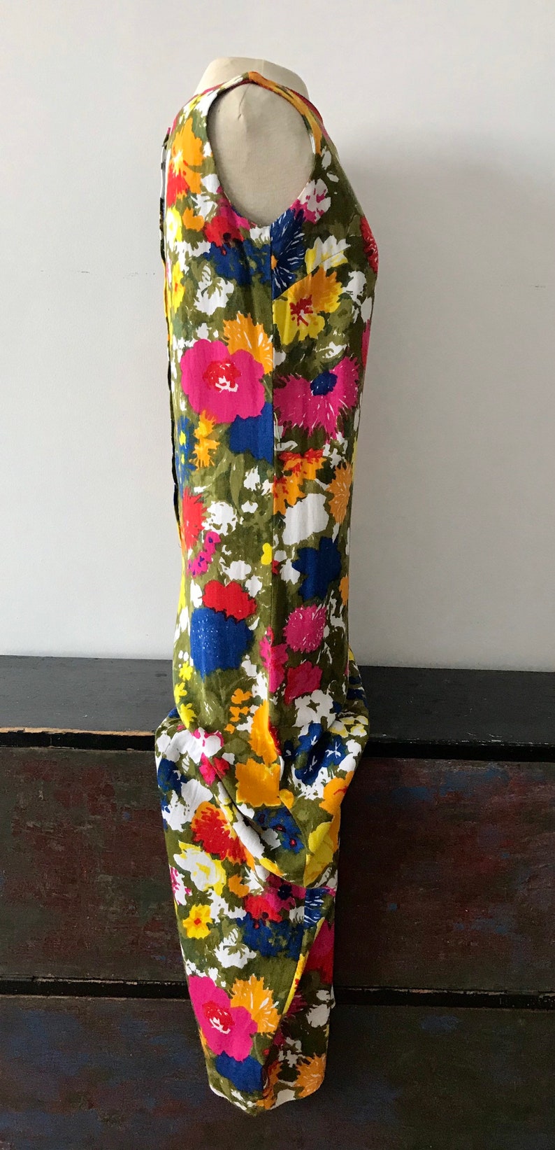 May include: A sleeveless maxi dress with a vibrant floral print featuring pink, yellow, red, blue, and green flowers on a white background.