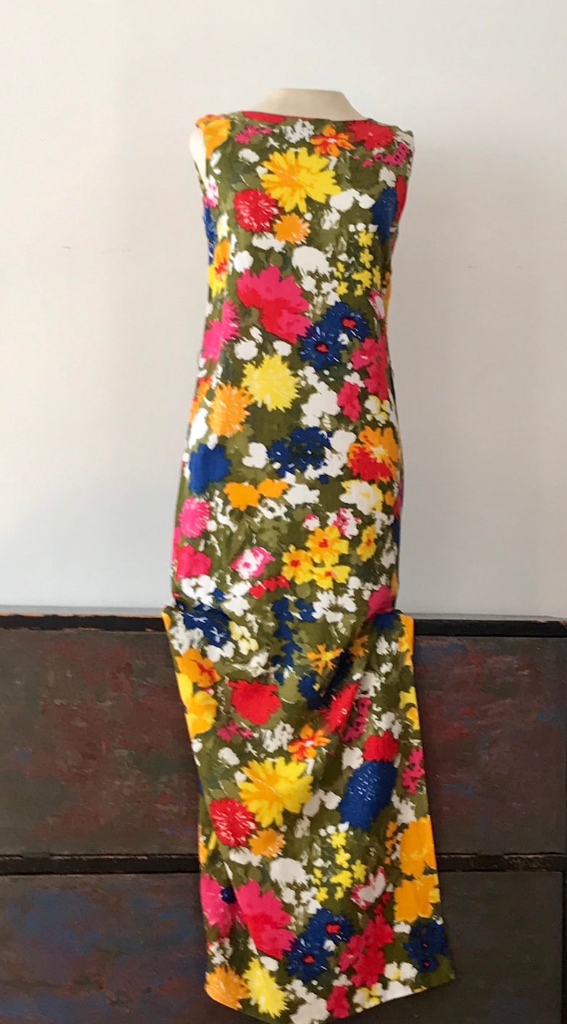 May include: A sleeveless maxi dress with a floral print in shades of red, yellow, blue, and white on a green background.