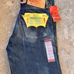 May include: A pair of blue denim jeans with a Levi's 501 label. The jeans are pre-shrunk and have a button fly. The label also states "America's Original Jeans - Since 1873".