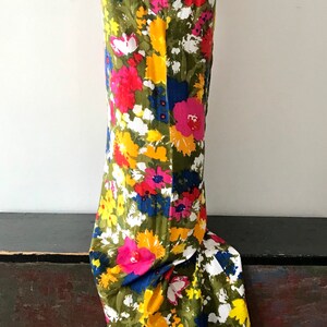 May include: A sleeveless maxi dress with a vibrant floral print featuring yellow, pink, red, blue, and white flowers on a green background.