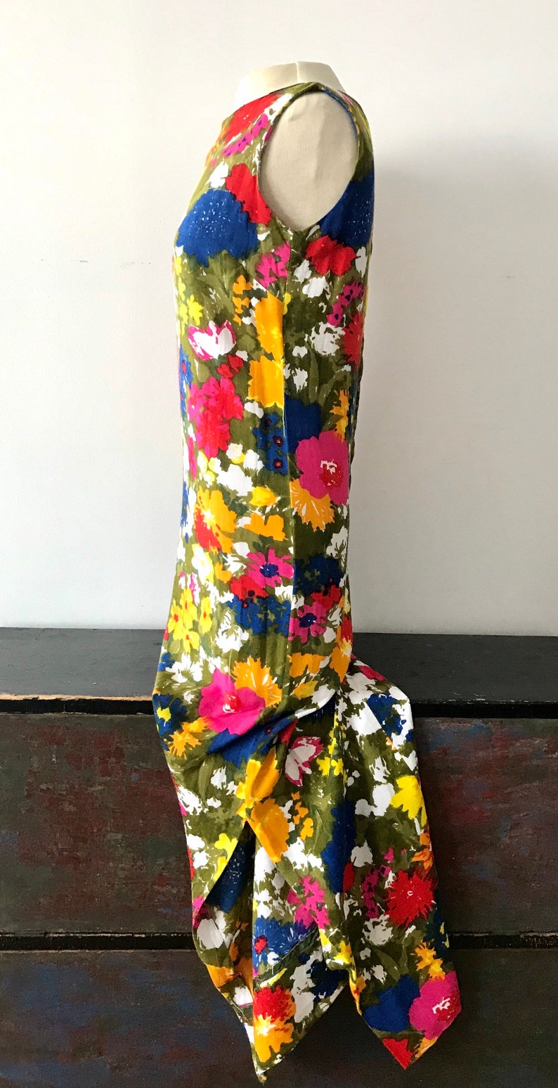May include: A sleeveless maxi dress with a vibrant floral print featuring yellow, pink, red, blue, and white flowers on a green background.