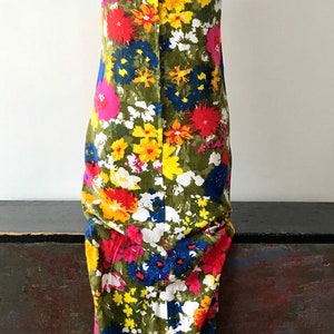 May include: A sleeveless maxi dress with a floral print in shades of pink, red, yellow, blue, and white on a green background.