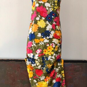May include: A sleeveless maxi dress with a floral print in shades of red, yellow, blue, and white on a green background.