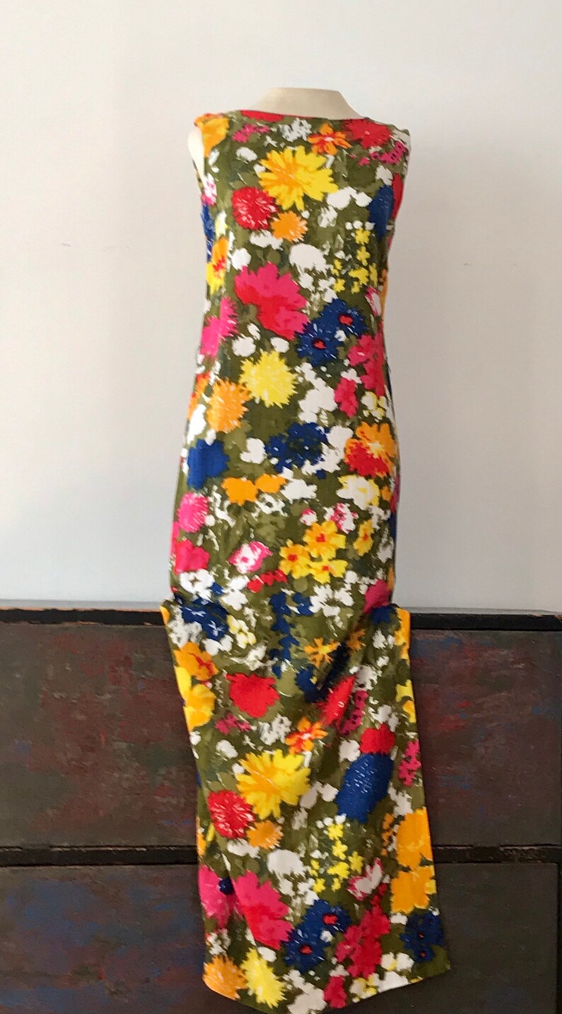May include: A sleeveless maxi dress with a floral print in shades of red, yellow, blue, and white on a green background.