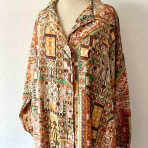 May include: A long-sleeved button-up shirt with a geometric pattern in shades of brown, green, and orange. The shirt has a collared neckline and a relaxed fit.