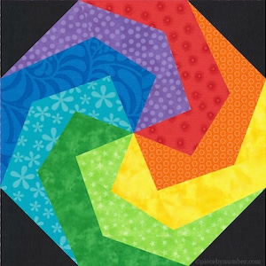 May include: A colorful quilt block with a geometric design. The block features a spiral pattern of various fabrics in shades of blue, green, yellow, orange, red, and purple. The fabrics have floral and polka dot patterns. The background is black.