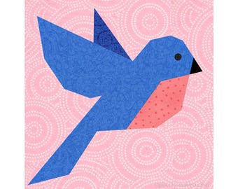 May include: A blue and pink origami bird with a black eye, flying against a pink background with white polka dots.