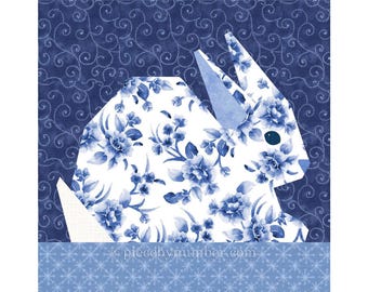 May include: A geometric rabbit design with a floral pattern in shades of blue and white. The rabbit is set against a dark blue background with a swirling pattern. The bottom of the image has a light blue border with a snowflake design. The text "piecebynumber.com" is visible.
