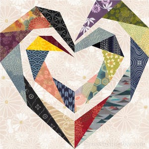 May include: A heart-shaped design made from colourful fabric scraps. The fabric is patterned with flowers, geometric shapes, and traditional Japanese designs. The background is a light beige with a white floral pattern.