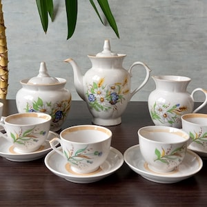Puede incluir: Un juego de té de porcelana vintage con un diseño floral. El juego incluye una tetera, una jarra de crema, un azucarero y seis tazas de té y platillos.