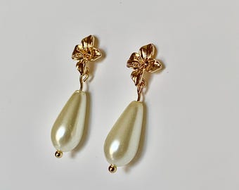 Petites boucles d'oreilles pendantes en forme de larme et de fleurs en or. Disponible en blanc ou ivoire nacré.