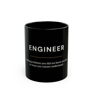 May include: Black ceramic mug with the word "ENGINEER" in white, above a gold line. Below, the text reads: "Solving problems you did not know you had in ways you cannot understand."