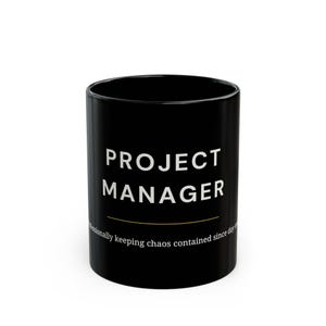 May include: Black ceramic mug with the words "PROJECT MANAGER" in white, above a thin gold line. Below the line, the text reads "Professionally keeping chaos contained since day one."