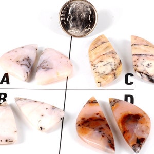 May include: Four pairs of pink and white agate cabochons with black dendritic inclusions. The cabochons are arranged in a grid pattern on a white surface. A US dime is included for scale.
