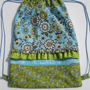 May include: A blue and green drawstring bag with a floral pattern. The bag has a ruffled trim and a zippered pocket.
