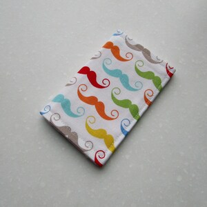 May include: A white fabric pouch with a colorful pattern of mustaches in red, orange, yellow, green, blue, and light blue.