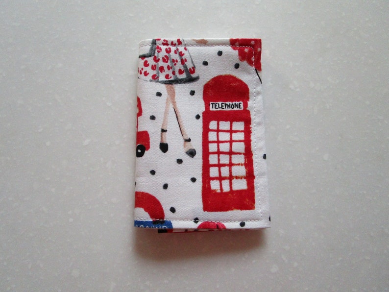 Puede incluir: Una bolsa de tela blanca con una cabina telef&oacute;nica roja, un coche rojo y una mujer con un vestido rojo con lunares negros. La bolsa tiene lunares negros y el texto "TELEPHONE" en la cabina telef&oacute;nica.