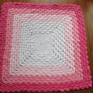 Pu&ograve; includere: Una copertina per neonati all'uncinetto con un centro bianco e un bordo sfumato rosa. La copertina &egrave; realizzata con un delicato motivo a punto e ha un bordo a festoni.