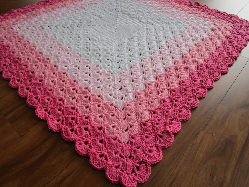 Pu&ograve; includere: Una copertina per neonati all'uncinetto con un design sfumato rosa e bianco. La copertina &egrave; realizzata con un delicato motivo a punto e ha un bordo a scalare.