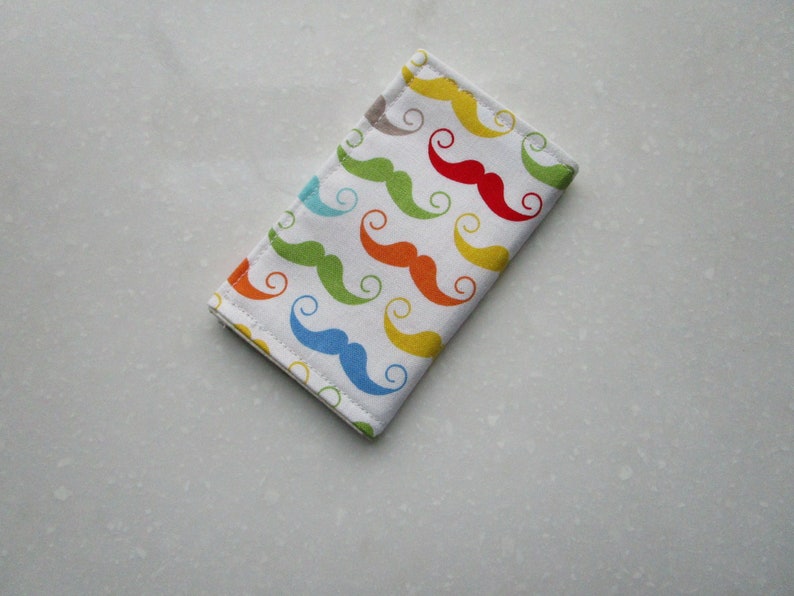 May include: A white fabric wallet with a colorful pattern of mustaches. The mustaches are in various colors, including red, yellow, blue, green, and orange.