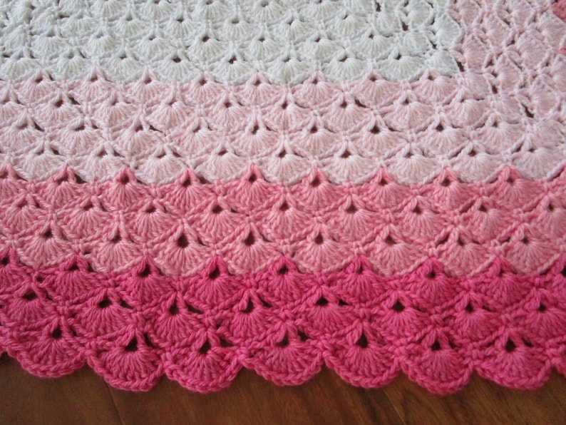 Pu&ograve; includere: Una copertina per neonati all'uncinetto con un bordo a scalare in tonalit&agrave; rosa e bianco.