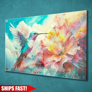 May include: Acrylic print featuring a watercolor painting of a hummingbird and a large flower. The hummingbird is depicted with blue, purple, and red hues, while the flower displays pink, yellow, and orange tones. The background includes clouds and a blue sky.
