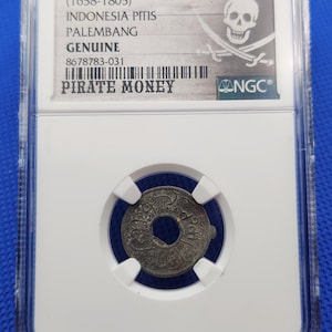 May include: A genuine Indonesian Pitis coin from Palembang, dating from 1658-1805, encased in a protective holder. The holder features the text "PIRATE MONEY" and a skull and crossbones design, indicating its historical significance.