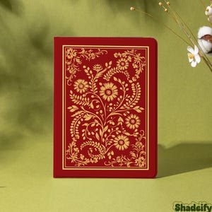 Könnte beinhalten: Ein rotes Notizbuch mit goldenem Blumendesign. Der Einband zeigt ein detailliertes Muster aus Blumen, Blättern und Ranken. Das Notizbuch hat eine rechteckige Form und einen goldenen Rand. Das Wort "Shadeify" befindet sich unten rechts.