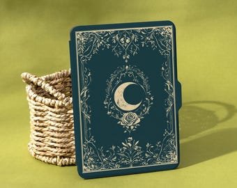 May include: A dark teal tablet case with an ornate design featuring a crescent moon, rose, and floral elements. The case is next to a woven basket on a light green surface. The brand name "Shadeify" is in the bottom right corner.