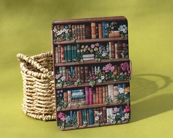 May include: A decorative case featuring a bookshelf design with colorful books and flowers. The case is brown with a floral and book design. A woven basket sits to the left of the case on a green background. The word "Shadeify" is in the bottom right corner.