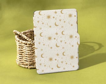 May include: A white tablet case with a celestial pattern of gold moons, stars, and suns. The case is next to a woven basket on a green surface. The brand name "Shadeify" is visible in the bottom right corner.