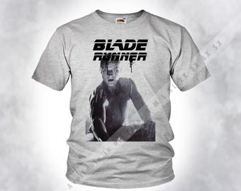 May include: A gray t-shirt with a black graphic print of a man's face and the text "BLADE RUNNER".